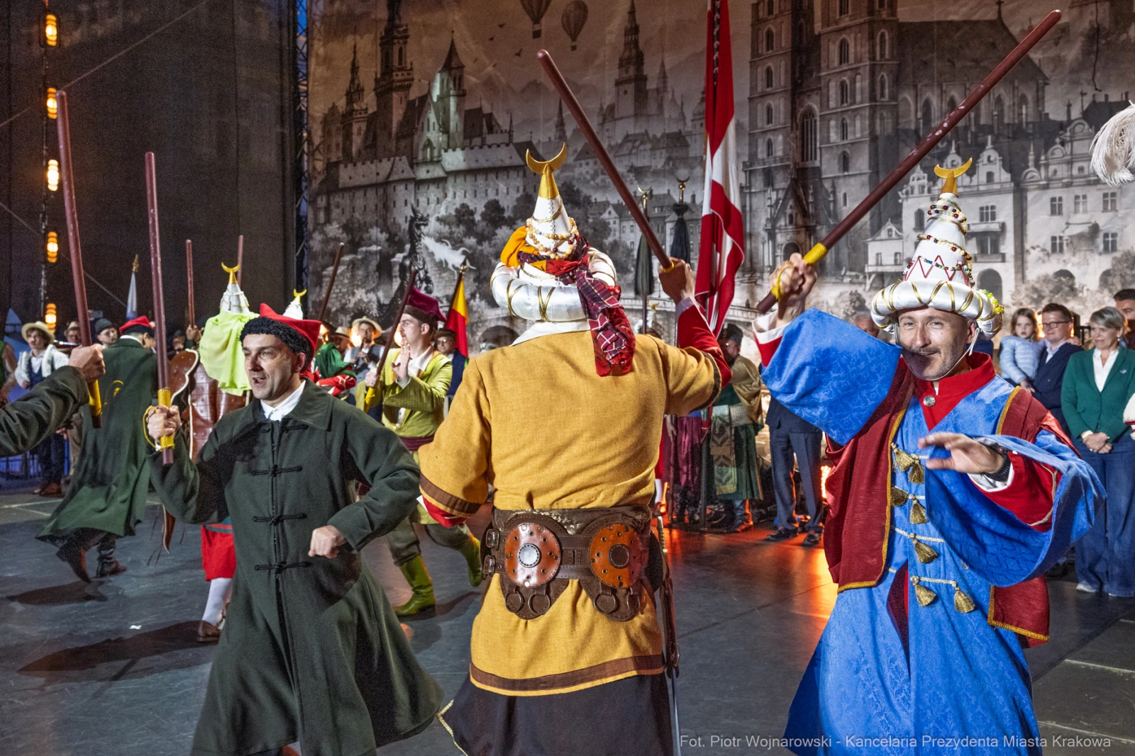 Grupa ludzi w tradycyjnych strojach, tańczących z kijami na scenie.  Autor: Piotr Wojnarowski