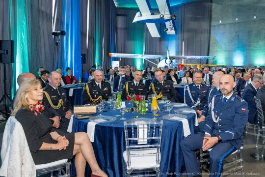 Uroczystość z udziałem wojskowych i cywilnych gości przy elegancko nakrytych stołach.