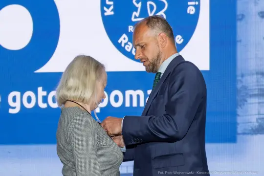 Wręczenie odznaczenia przez mężczyznę kobiecie podczas ceremonii.