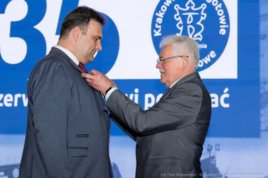 Uroczystość wręczenia odznaczenia mężczyźnie w garniturze.