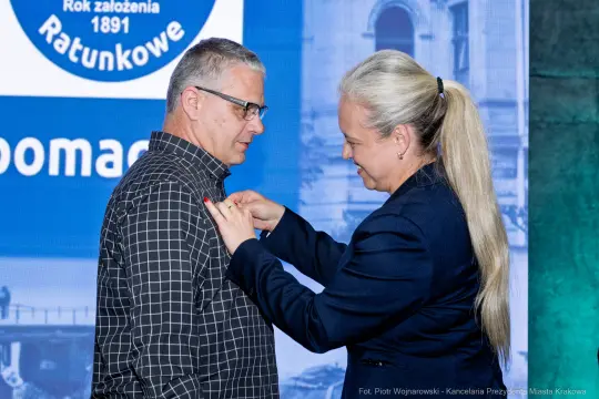 Wręczenie odznaczenia mężczyźnie przez kobietę podczas uroczystości.