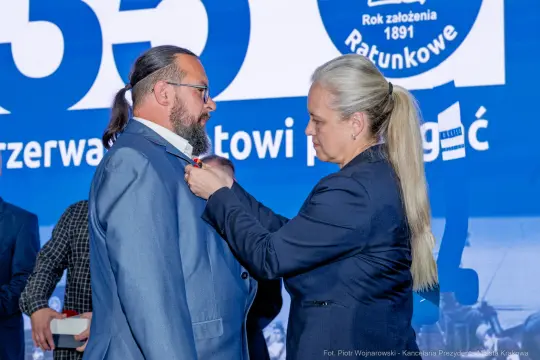 Mężczyzna otrzymuje odznaczenie od kobiety podczas uroczystości.