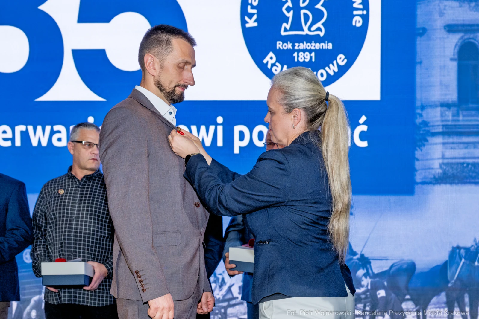 Mężczyzna odbiera odznaczenie od kobiety podczas uroczystości.  Autor: Piotr Wojnarowski