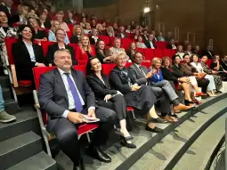 Grupa ludzi siedzących na widowni w teatrze, uśmiechających się i bawiących się.