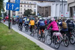 Tłum rowerzystów na ulicy, z oznaczeniem drogi dla autobusów i taksówek.