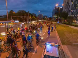 Grupa rowerzystów na ulicy w mieście, nocne oświetlenie, ruch uliczny.