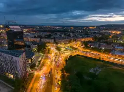 Widok na miasto nocą z oświetlonymi ulicami i budynkami.