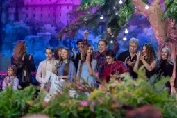 Na scenie pod drzewem ozdobionym lampkami stoją polscy artyści z dziećmi – laureatami konkursu. W tle Wawel. Plenerowa scena i światła tworzą uroczystą, radosną atmosferę wydarzenia.