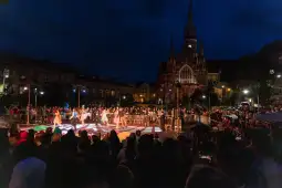 Taniec na ulicy w nocy, tłum ludzi, oświetlona architektura w tle.