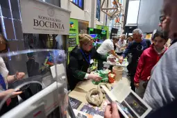 Kobieta przy stoisku Kopalni Soli Bochnia, prezentująca produkty i materiały promocyjne.