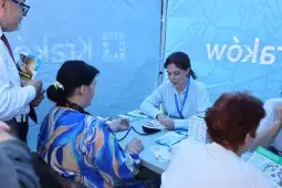 Kobieta mierzy ciśnienie krwi innej kobiecie w namiocie informacyjnym.