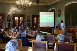 Konferencja w sali z prelegentką i uczestnikami, prezentacja na ekranie.