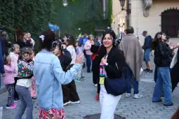 Ludzie tańczą na ulicy w słuchawkach, wśród dzieci i dorosłych, w radosnej atmosferze.