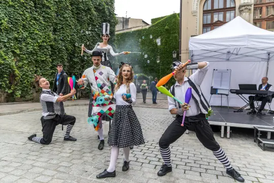 Grupa artystów cyrkowych wykonujących sztuczki z kulami i kijami na ulicy.