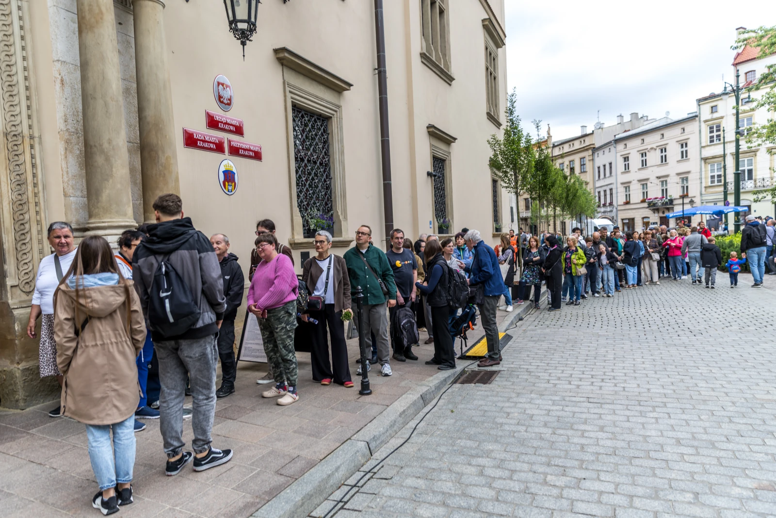 Ludzie stoją w kolejce przy budynku w mieście.  Autor: Bogusław Świerzowski