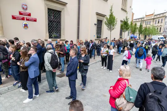 Tłum ludzi czekających w kolejce przed budynkiem.