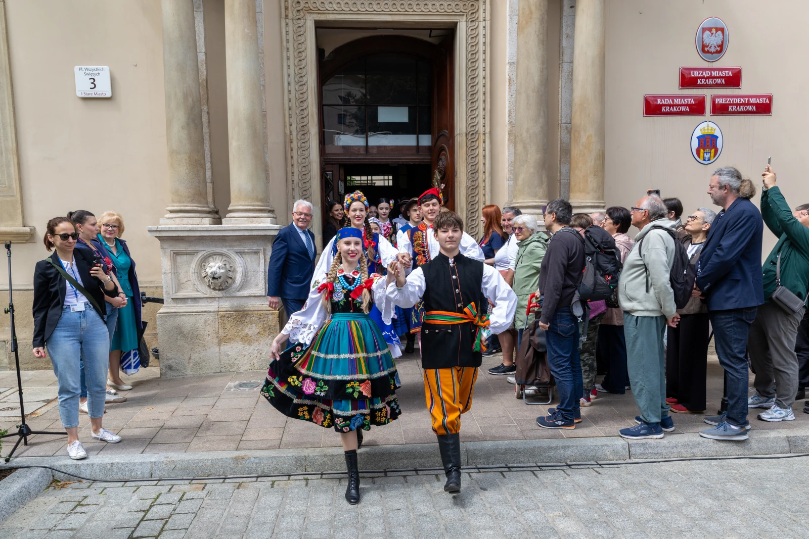 Grupa ludzi w tradycyjnych strojach ludowych na tle budynku.  Autor: Bogusław Świerzowski