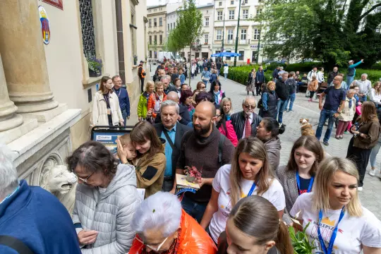Tłum ludzi czekających w kolejce przed budynkiem w mieście.