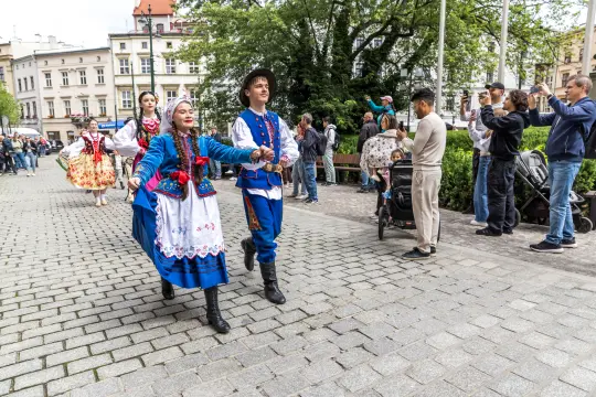 Tradycyjne tańce ludowe w strojach regionalnych na ulicach miasta.