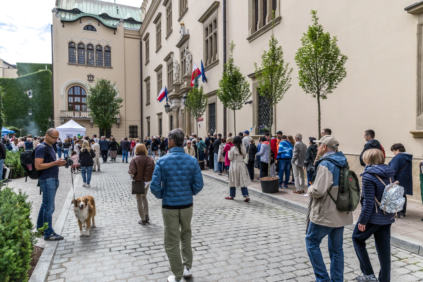 Tłum ludzi czekających w kolejce przed budynkiem z flagami.  Autor: Bogusław Świerzowski