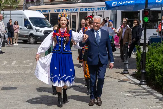 Kobieta w tradycyjnym stroju ludowym i mężczyzna w garniturze idą razem ulicą.