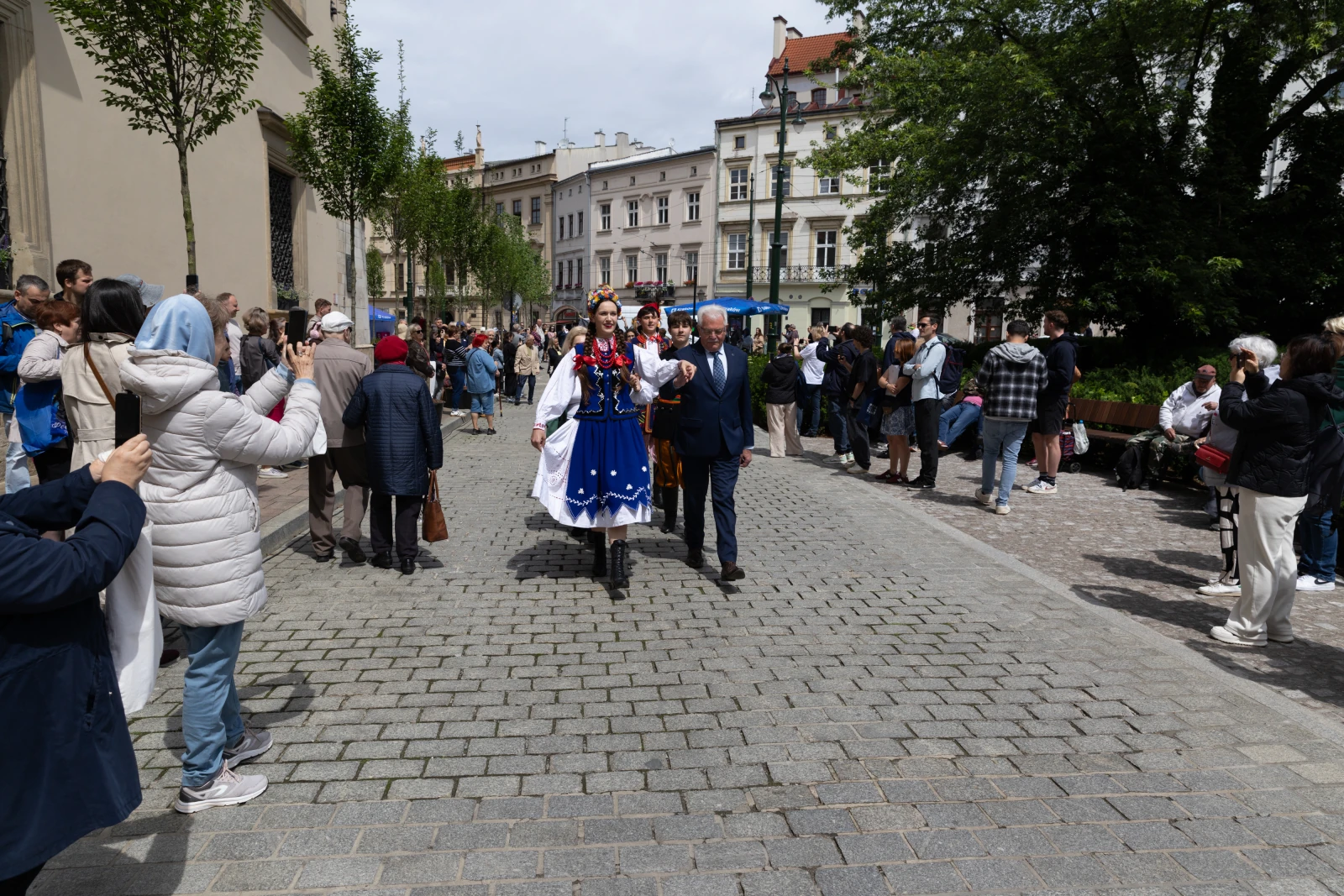 Parada w tradycyjnych strojach ludowych na ulicy, z tłumem ludzi w tle.  Autor: Bogusław Świerzowski