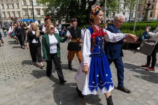 Grupa ludzi w tradycyjnych strojach ludowych podczas parady.