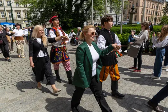 Grupa osób w tradycyjnych strojach ludowych podczas parady w mieście.
