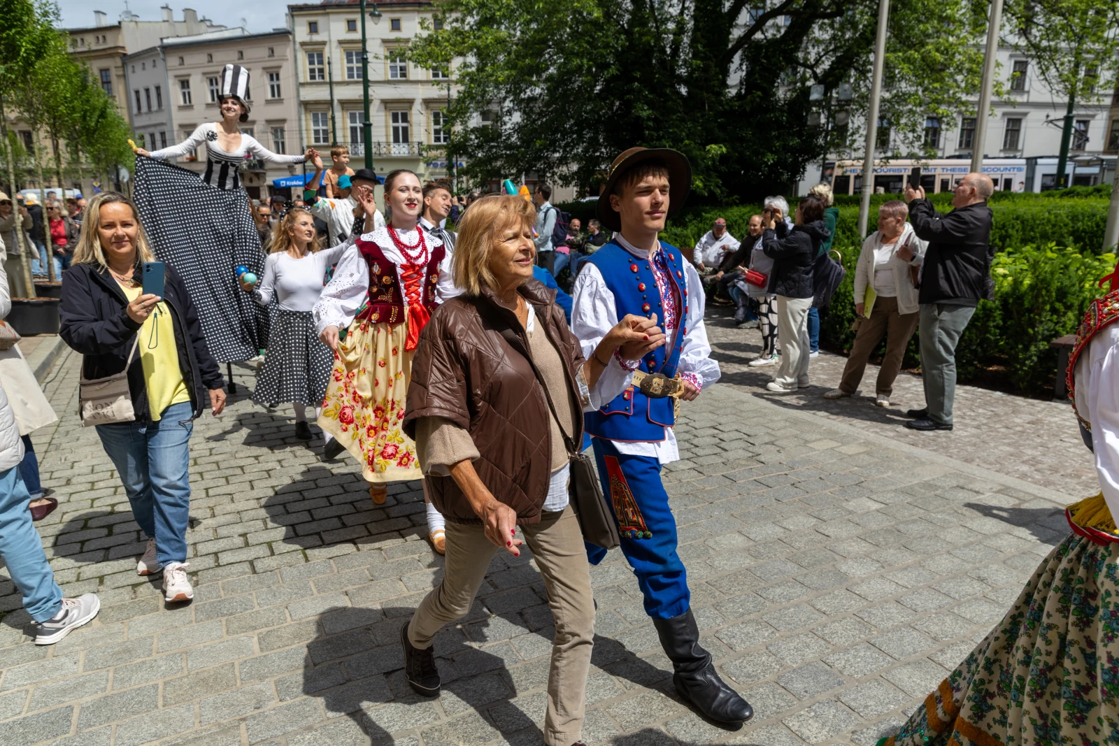 Grupa osób w tradycyjnych strojach ludowych podczas parady w mieście.  Autor: Bogusław Świerzowski