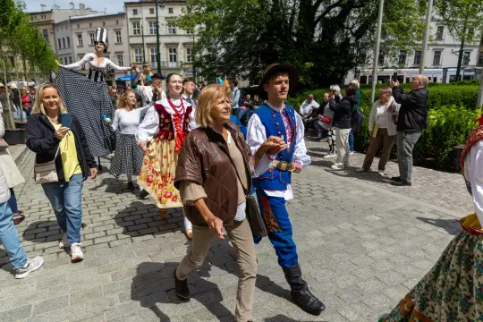 Grupa osób w tradycyjnych strojach ludowych podczas parady w mieście.