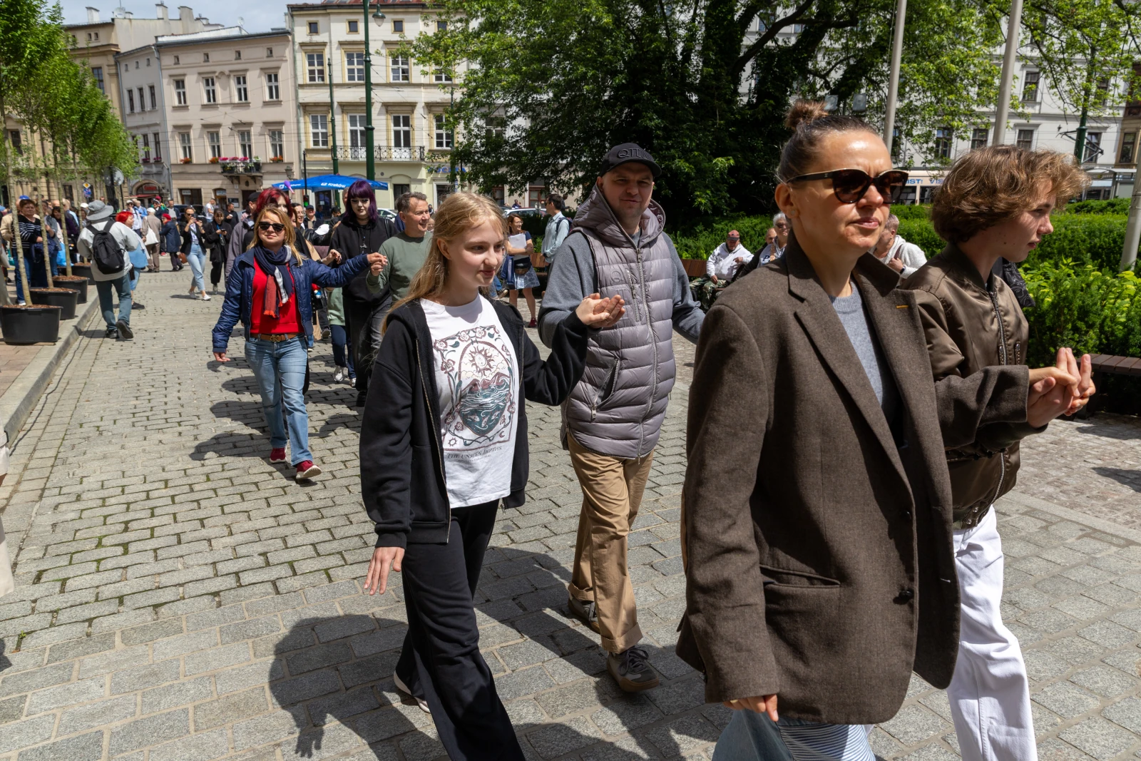 Grupa ludzi spacerujących po ulicy w mieście.  Autor: Bogusław Świerzowski