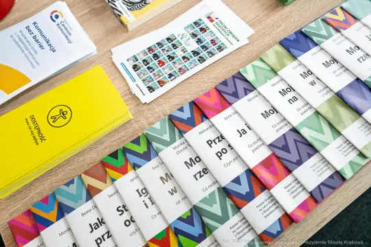Materiały informacyjne i ulotki na stole, różnorodne kolory i wzory.