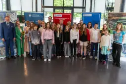Grupa dzieci i dorosłych na wydarzeniu w Krakowie, z banerami promującymi miasto.