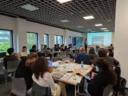 Grupa ludzi uczestniczy w warsztatach w sali konferencyjnej.