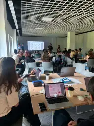 Spotkanie w sali konferencyjnej z uczestnikami pracującymi przy laptopach.