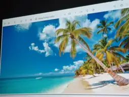 Plaża z palmami, turkusowa woda i błękitne niebo z białymi chmurami.