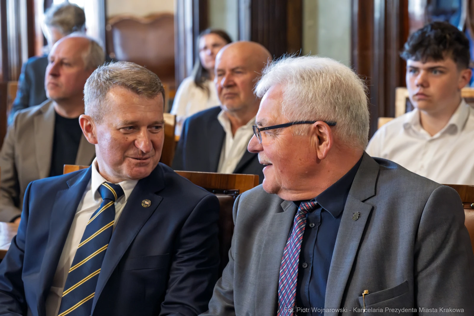 Dwóch mężczyzn rozmawia w sali, w tle siedzą inni uczestnicy spotkania.  Autor: Piotr Wojnarowski