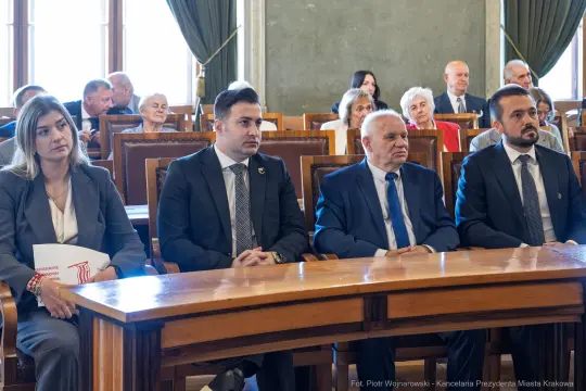 Grupa osób siedzących przy stole w sali obrad.
