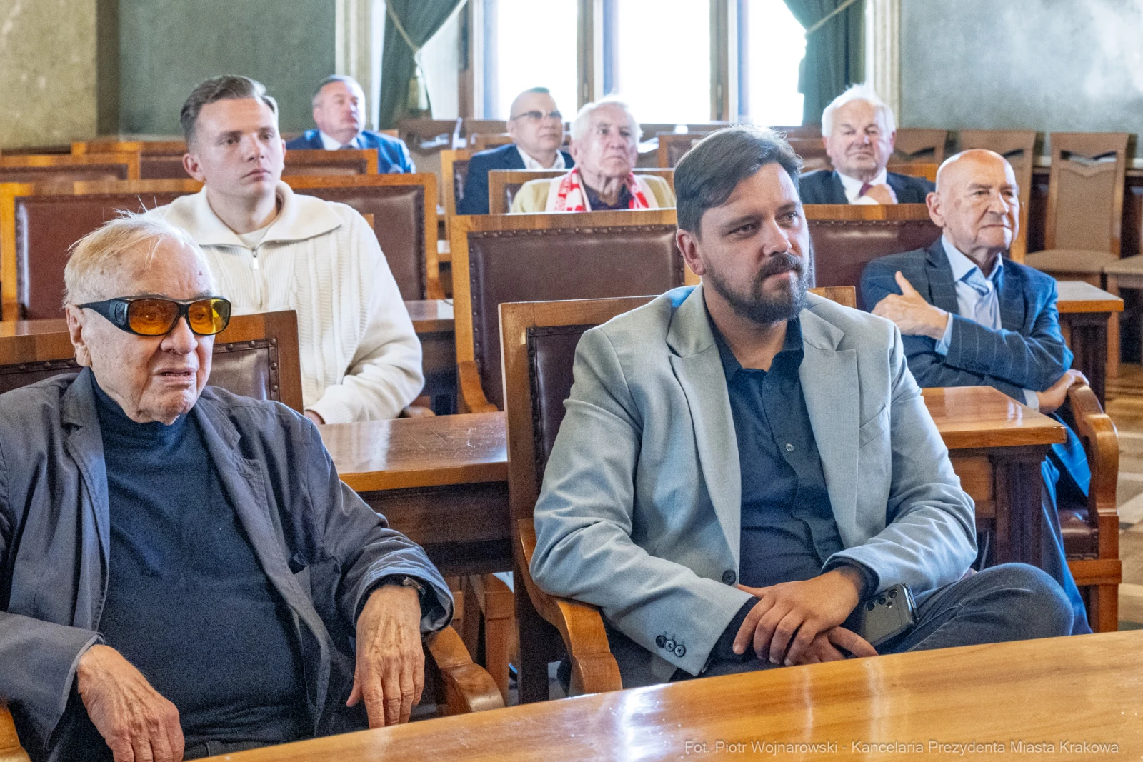 Grupa mężczyzn siedzących w sali, niektórzy w okularach przeciwsłonecznych, w trakcie spotkania.  Autor: Piotr Wojnarowski