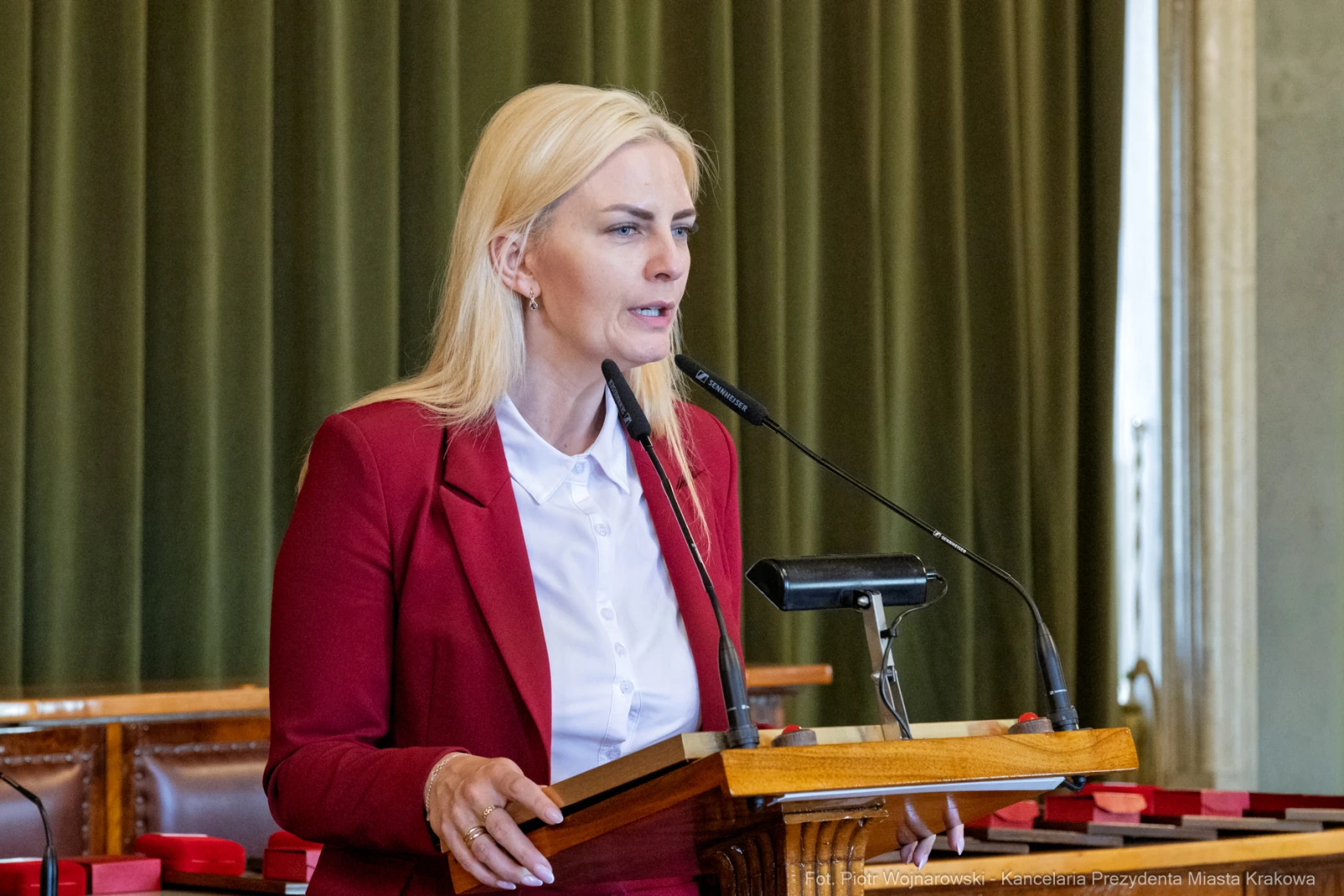 Kobieta w czerwonym żakiecie przemawia z mównicy w sali obrad.  Autor: Piotr Wojnarowski