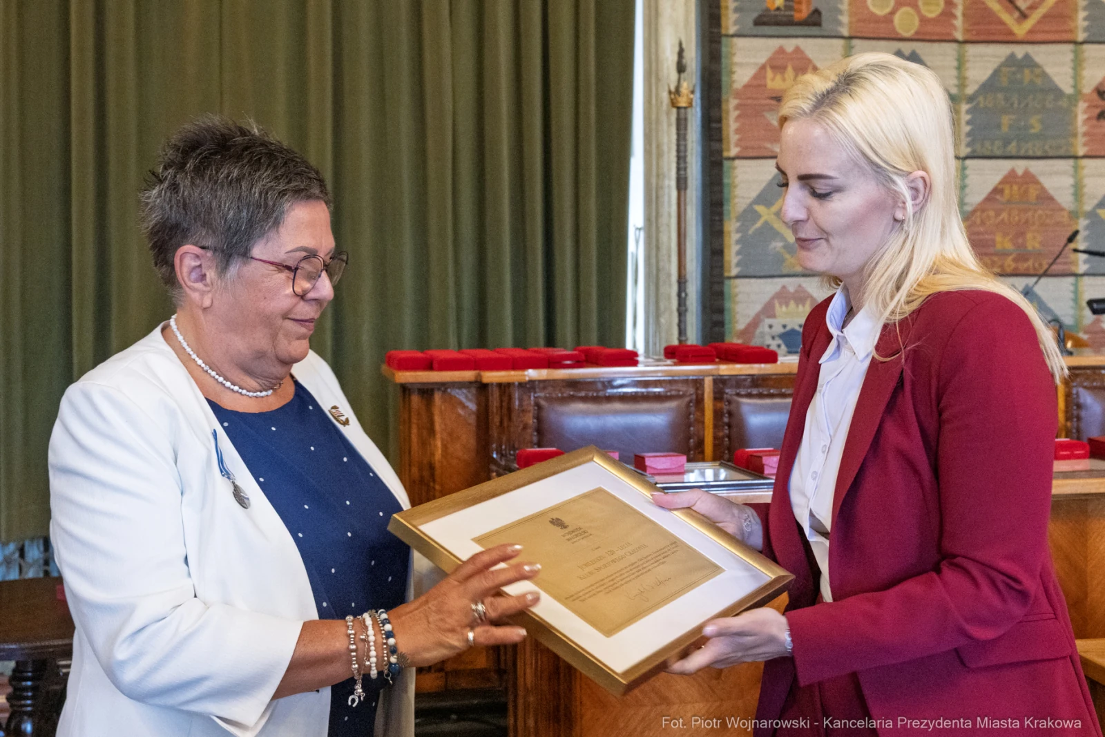 Wręczenie nagrody przez kobietę w białej bluzce drugiej kobiecie w czerwonej marynarce.  Autor: Piotr Wojnarowski