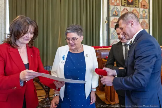 Wręczenie odznaczeń w sali obrad, uczestnicy w formalnych strojach.