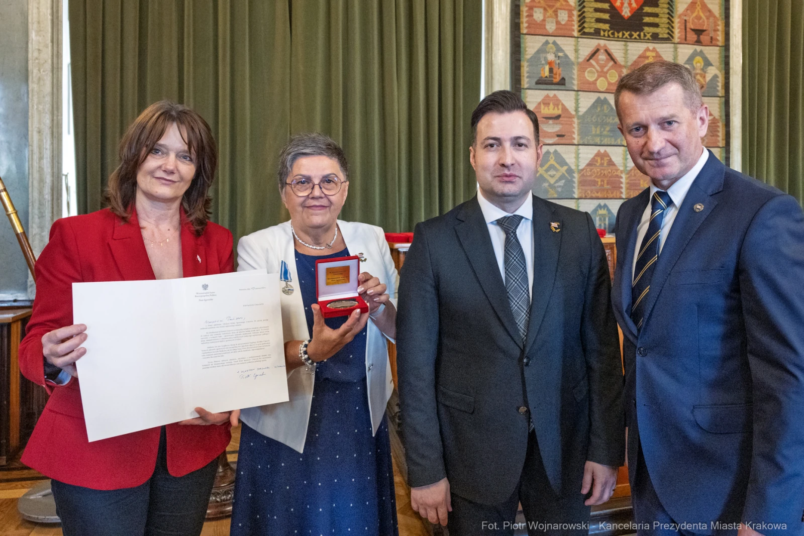 Wręczenie odznaczenia w uroczystej atmosferze, cztery osoby z medalem i dokumentem.  Autor: Piotr Wojnarowski
