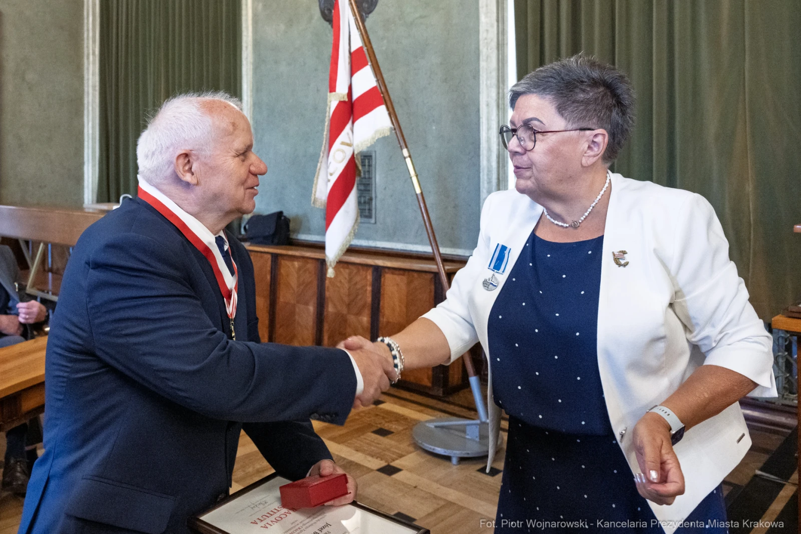 Uroczystość wręczenia odznaczeń, uścisk dłoni między dwiema osobami.  Autor: Piotr Wojnarowski