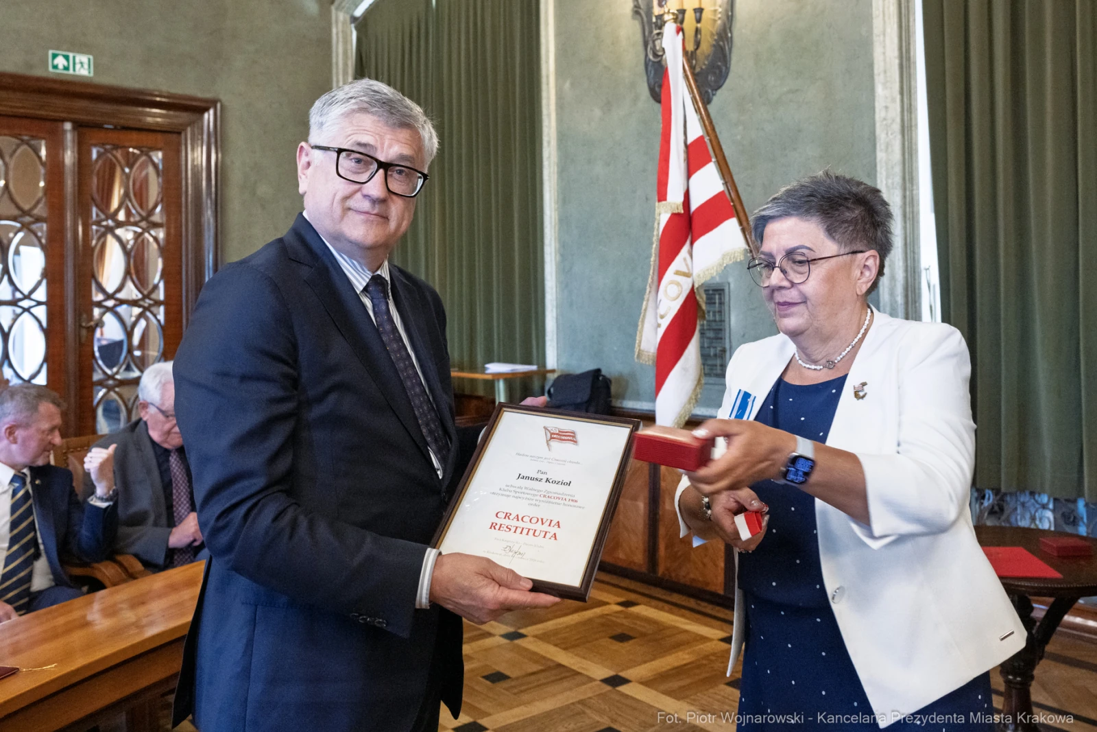 Wręczenie nagrody przez kobietę mężczyźnie w formalnym otoczeniu.  Autor: Piotr Wojnarowski