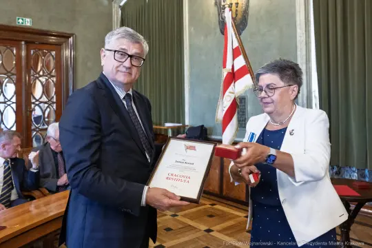 Wręczenie nagrody przez kobietę mężczyźnie w formalnym otoczeniu.