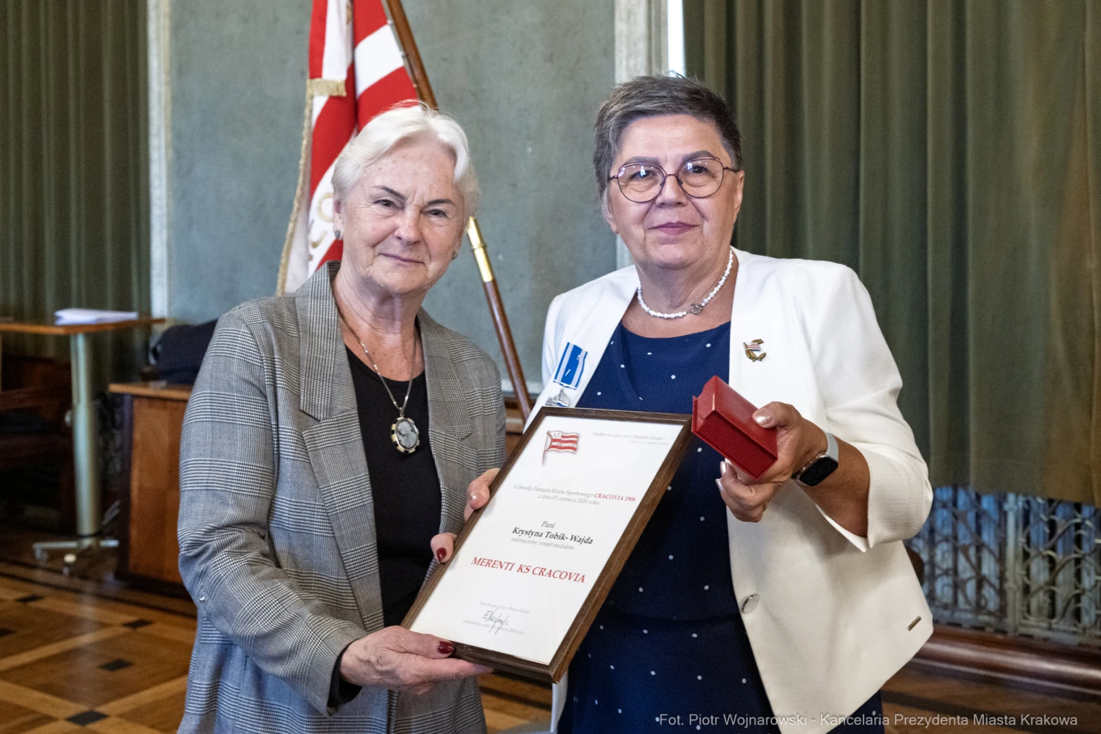 Dwie kobiety trzymają dyplom oraz medal w sali z flagą.  Autor: Piotr Wojnarowski