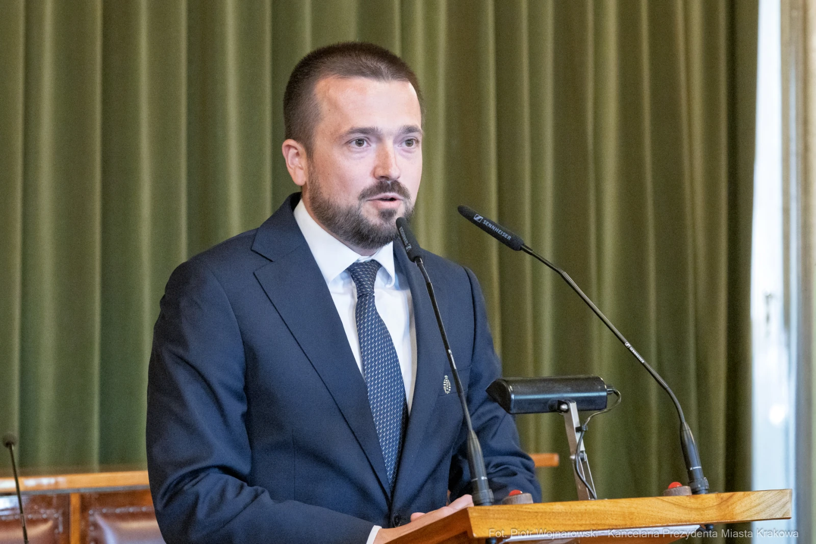 Mężczyzna w garniturze przemawia przy mównicy w sali obrad.  Autor: Piotr Wojnarowski