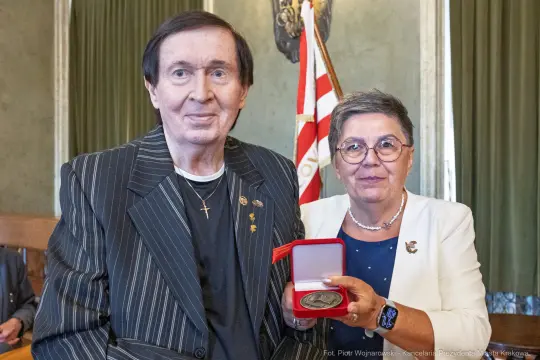 Mężczyzna i kobieta trzymają medal w eleganckim otoczeniu.