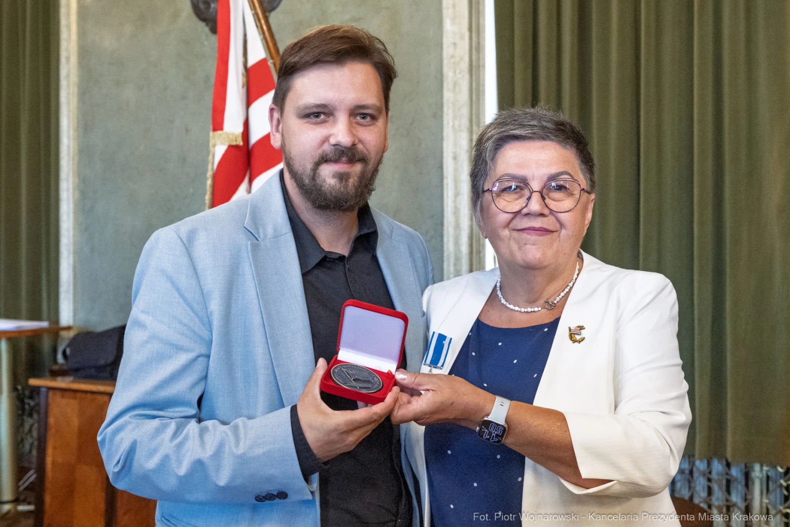 Mężczyzna i kobieta trzymają medal w eleganckim otoczeniu.  Autor: Piotr Wojnarowski